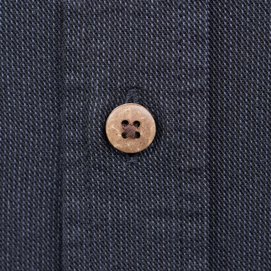 Close-up of a dark navy textured fabric with a single round light brown button on the front.