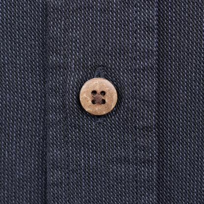 Close-up of a dark navy textured fabric with a single round light brown button on the front.
