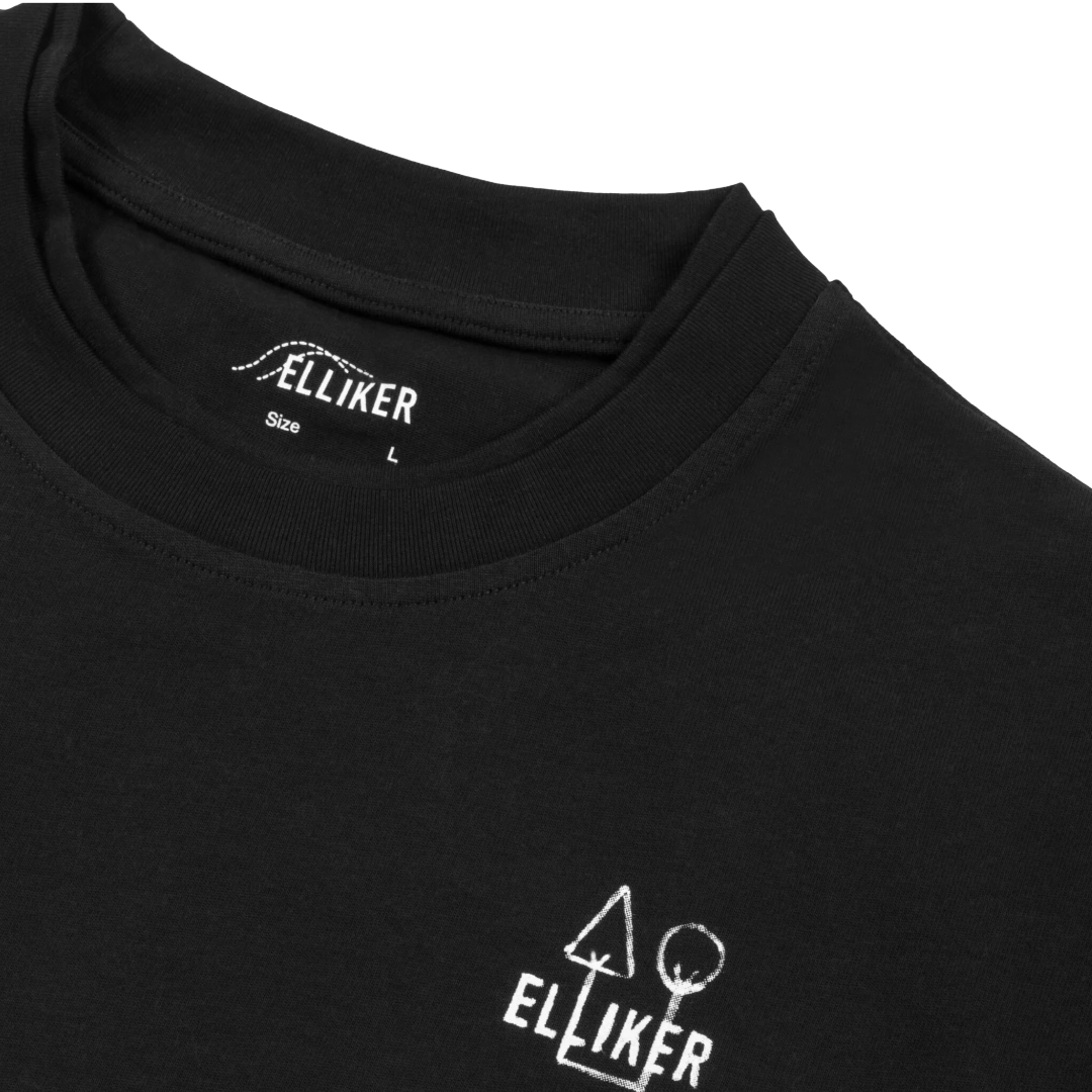 Close-up of a black crewneck t-shirt by Elliker, showing the inner neck label and a white graphic logo printed on the lower left chest.