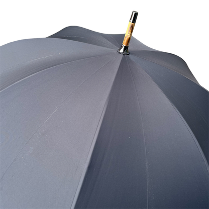 Close-up top view of a dark gray umbrella canopy with a wooden handle and black metal cap on a white background.
