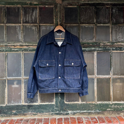 Blue denim jacket hanging on a brick wall with a tiled section above