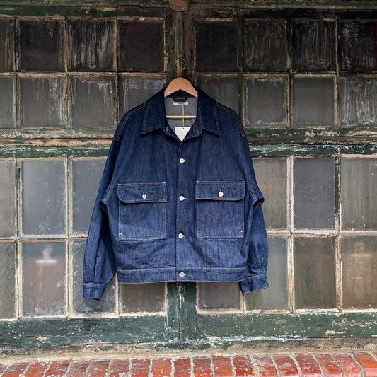 Blue denim jacket hanging on a brick wall with a tiled section above