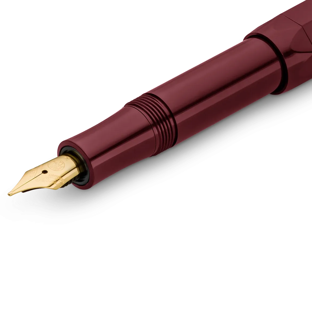 Close-up of a fountain pen with a metallic burgundy barrel and a gold nib, shown on a clean white background.