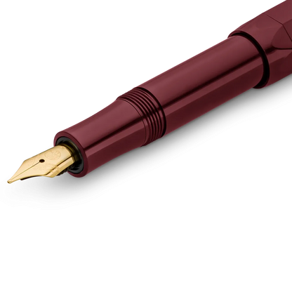 Close-up of a fountain pen with a metallic burgundy barrel and a gold nib, shown on a clean white background.