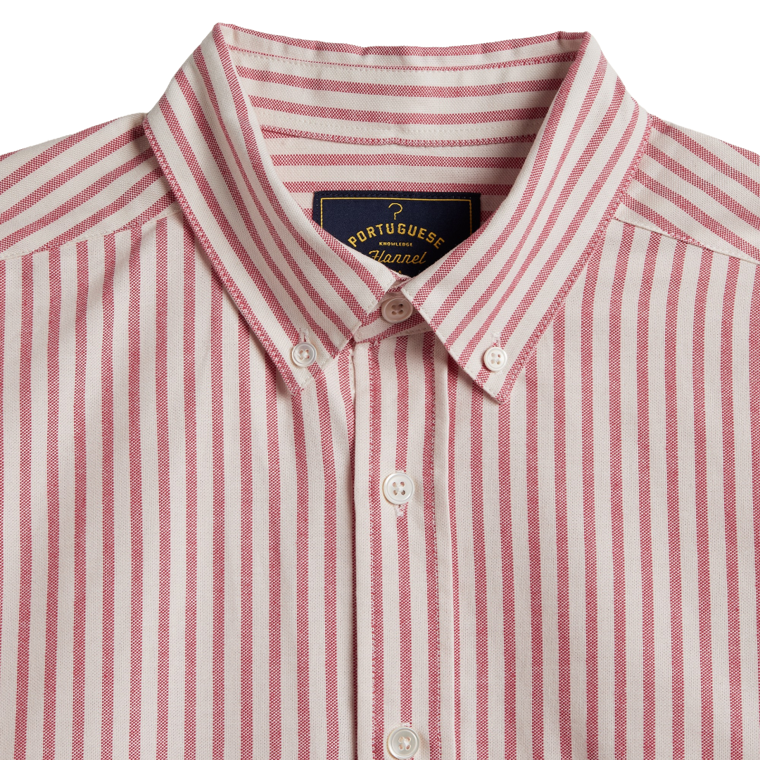 Close-up of a Portuguese shirt button-down shirt with vertical pink and white stripes, featuring a pointed collar and white buttons.