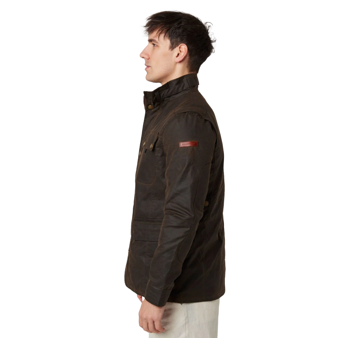 A man shown in profile wearing a dark brown waxed cotton jacket with a small red Barbour logo patch on the upper sleeve, paired with off-white trousers, against a plain white background.