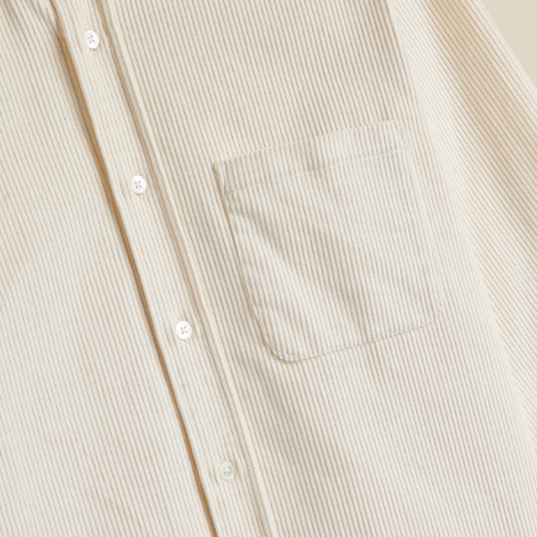 Close-up of a cream-colored corduroy button-up shirt with a chest pocket and white buttons.