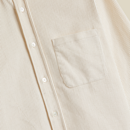 Close-up of a cream-colored corduroy button-up shirt with a chest pocket and white buttons.