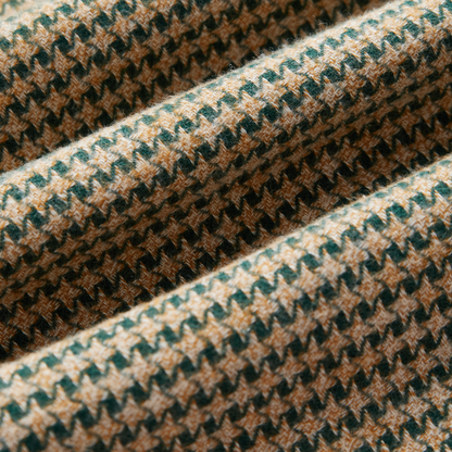 A close-up of a textured fabric with a woven houndstooth pattern in beige, brown, and dark green.