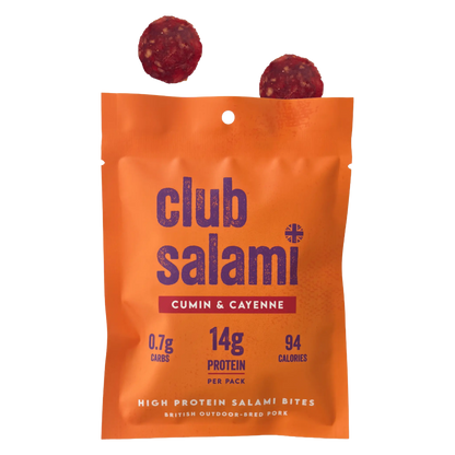 An orange stand-up pouch of Club Salami Cumin & Cayenne high protein salami bites, with two round salami slices floating above the bag on a white background.