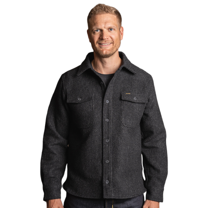 A man wearing a dark charcoal gray textured button-up overshirt with chest pockets, photographed against a solid white background.