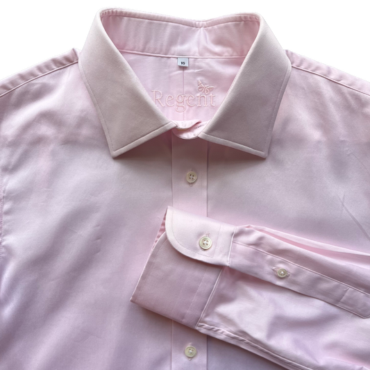 A light pink long-sleeve dress shirt with a spread collar and folded cuff, shown on a plain white background. The brand name 'Regent' is embroidered on the inner neck label.