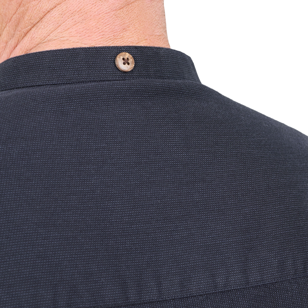 Close-up of the back collar of a dark navy textured shirt, showing a single brown button and the back of a person's neck.