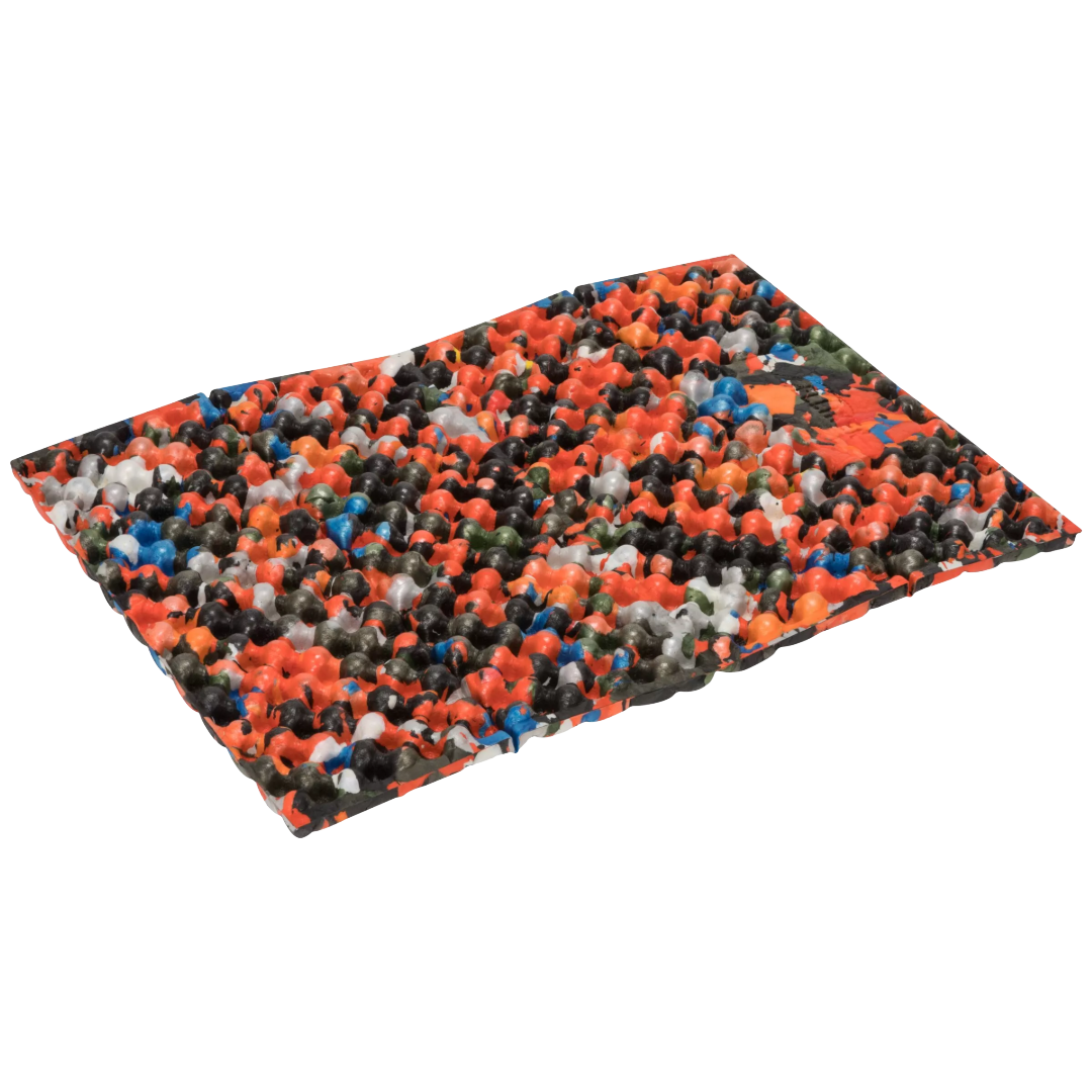 A rectangular mat covered in a dense multicolor pattern of small plastic-like pieces, shown at an angle on a plain white background.
