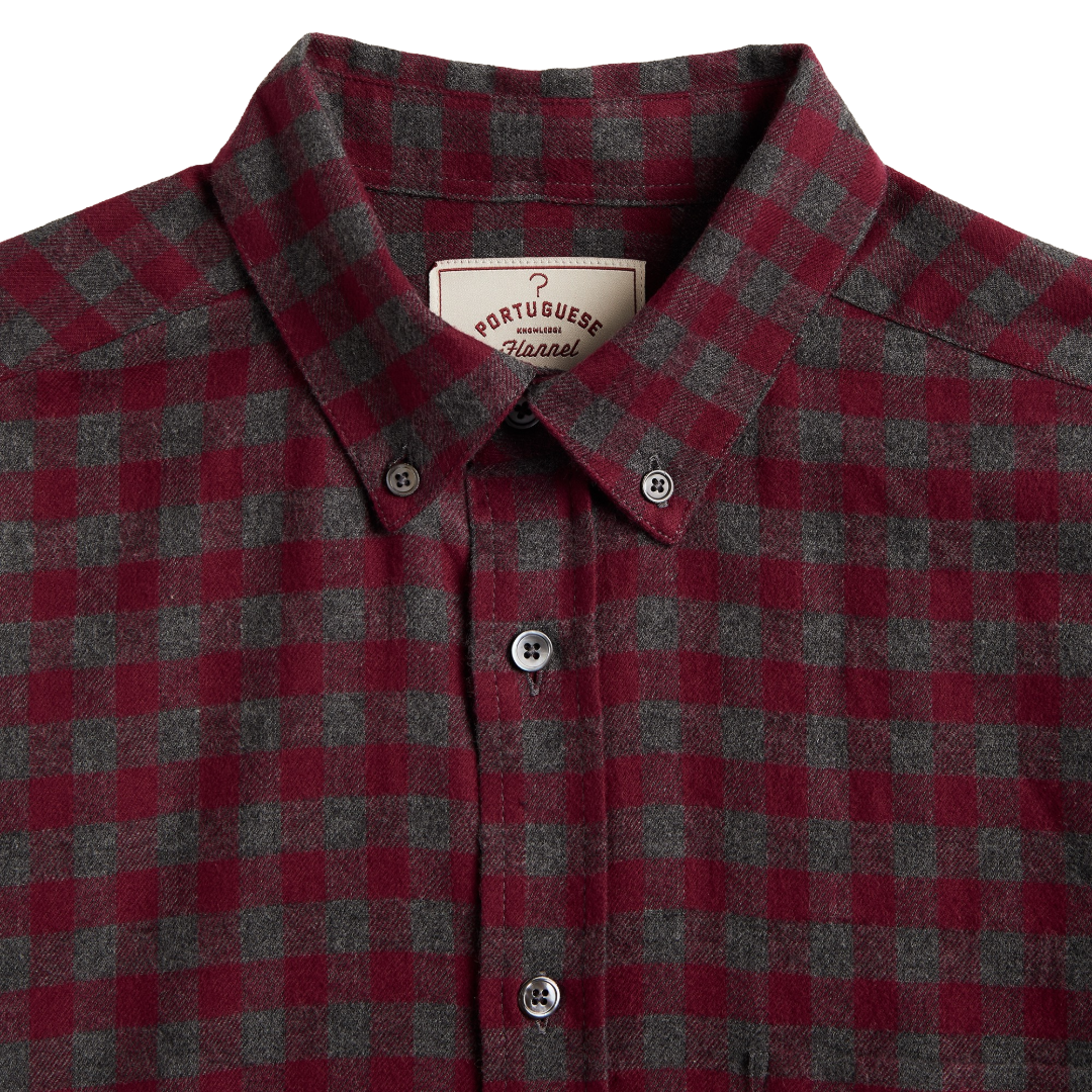 Close-up of a Portuguese Check plaid button-down shirt in red and dark gray wool, featuring a classic collar and white buttons.