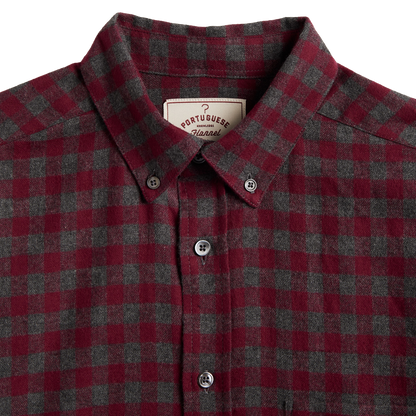 Close-up of a Portuguese Check plaid button-down shirt in red and dark gray wool, featuring a classic collar and white buttons.