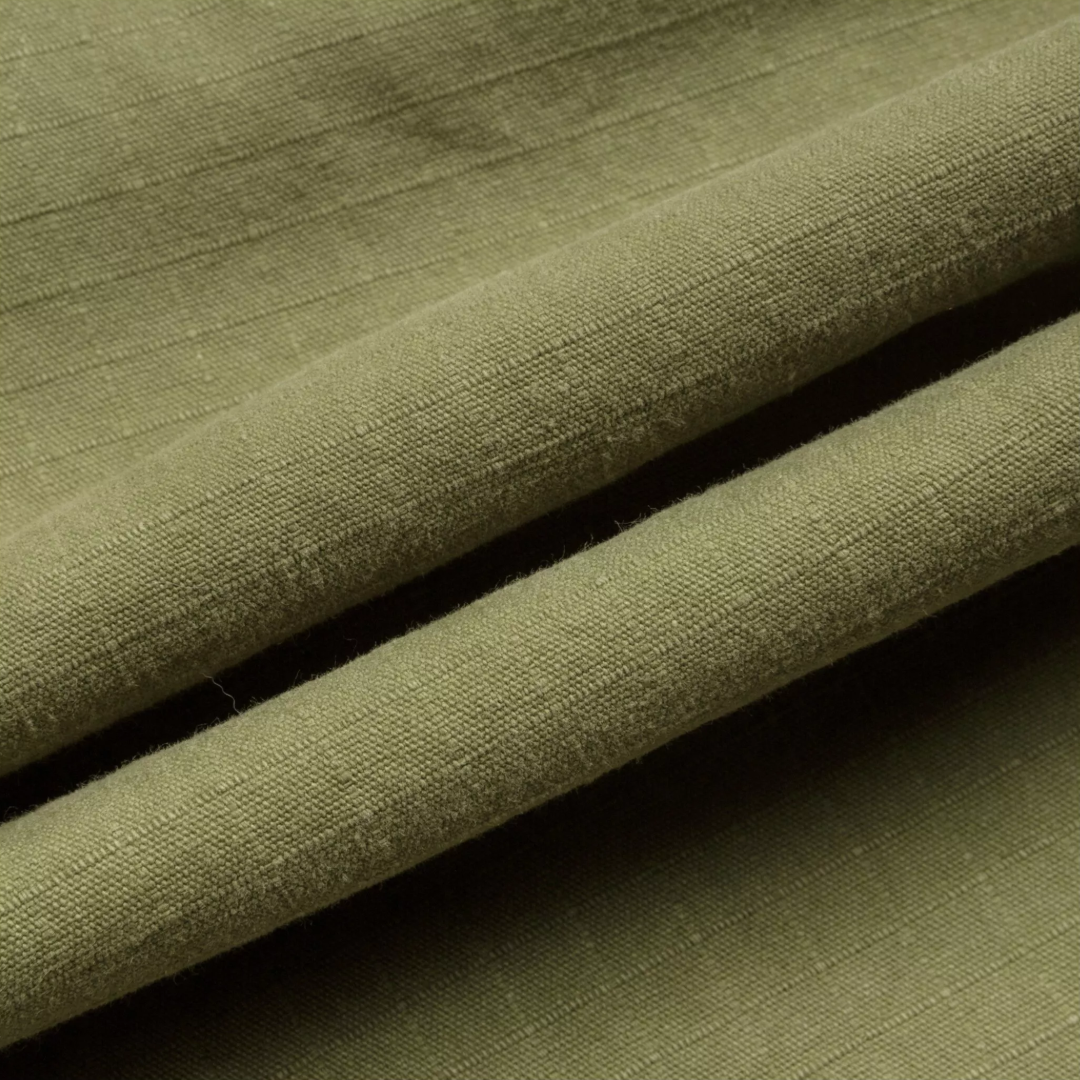 A close-up of olive green textured fabric with soft folds and a fine woven ribbed pattern.