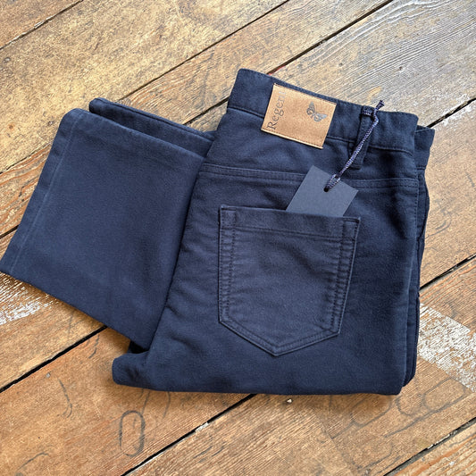 Folded navy blue jeans with a tag on a wooden surface