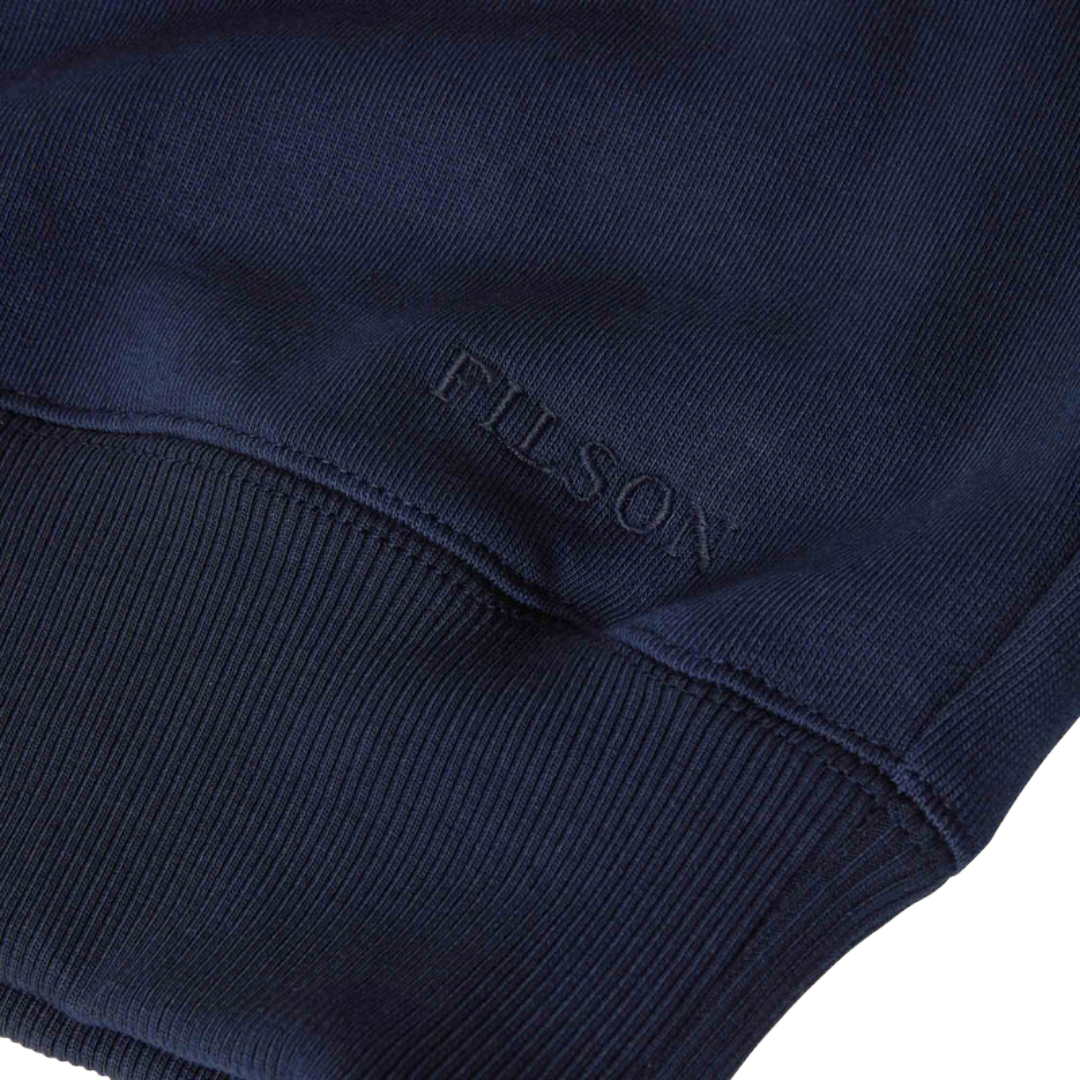 Close-up of a navy blue ribbed knit garment, showing the embossed FILSON brand name near the cuff.