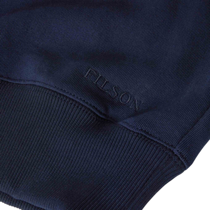 Close-up of a navy blue ribbed knit garment, showing the embossed FILSON brand name near the cuff.