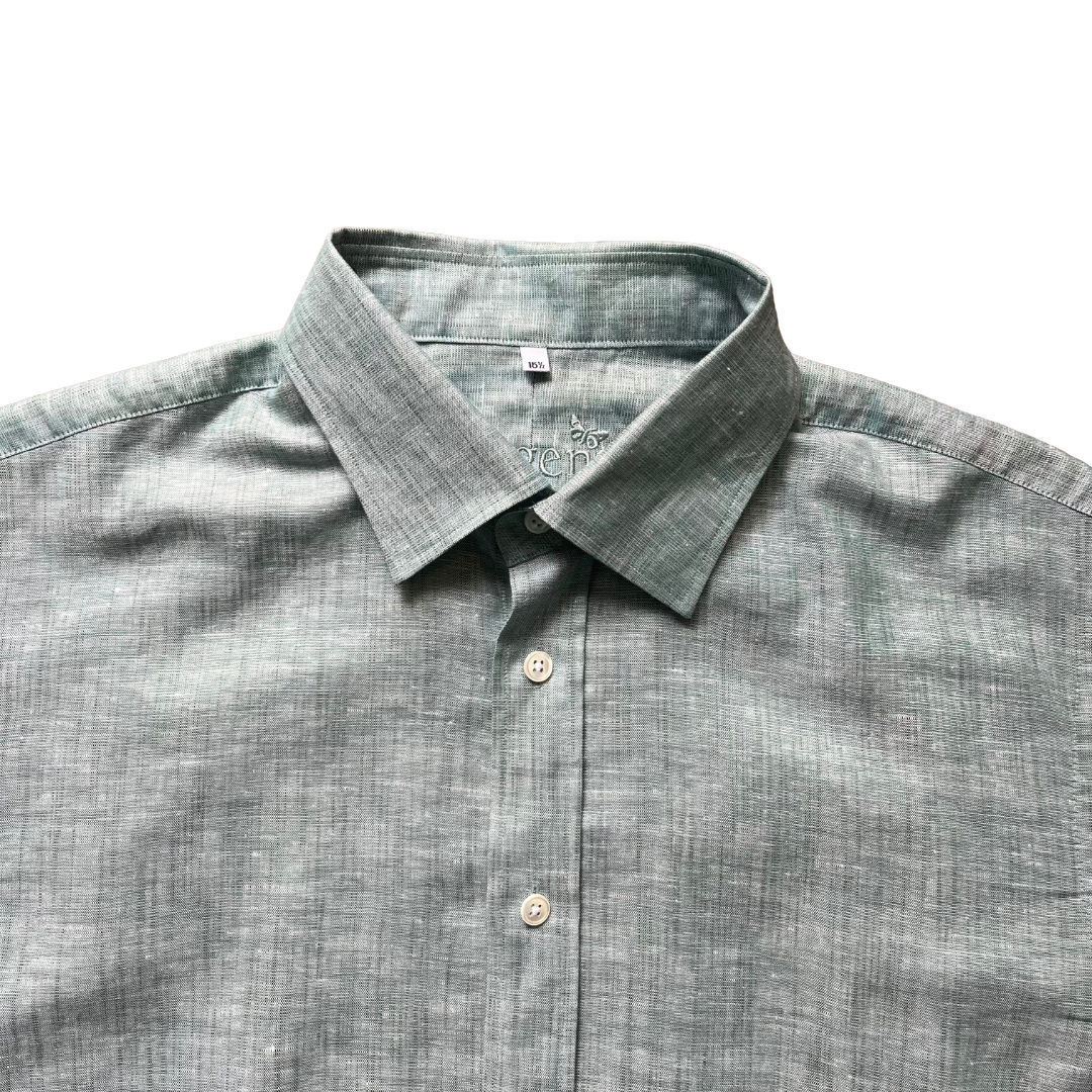 A close-up of a men's long-sleeve button-down shirt in a textured sage green fabric, showing the collar, button placket, and inner neck label.