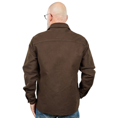 A man viewed from the back wearing a dark brown long-sleeve button-up shirt and blue jeans against a plain white background.
