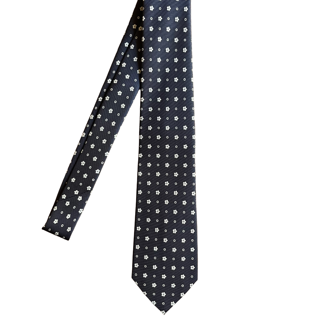 A dark navy necktie with a small white floral and dot pattern, shown against a plain white background.