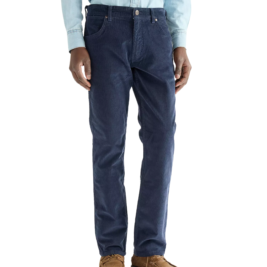A person wearing dark blue slim-fit jeans, a light blue long-sleeve button-up shirt, and brown shoes, shown from the waist down against a plain white background.