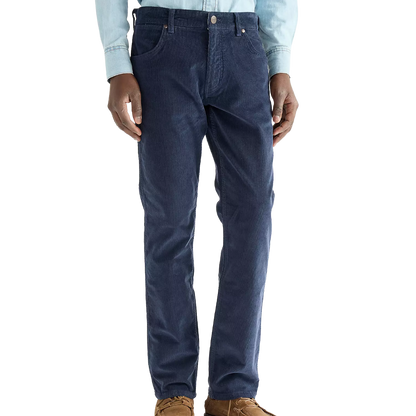 A person wearing dark blue slim-fit jeans, a light blue long-sleeve button-up shirt, and brown shoes, shown from the waist down against a plain white background.