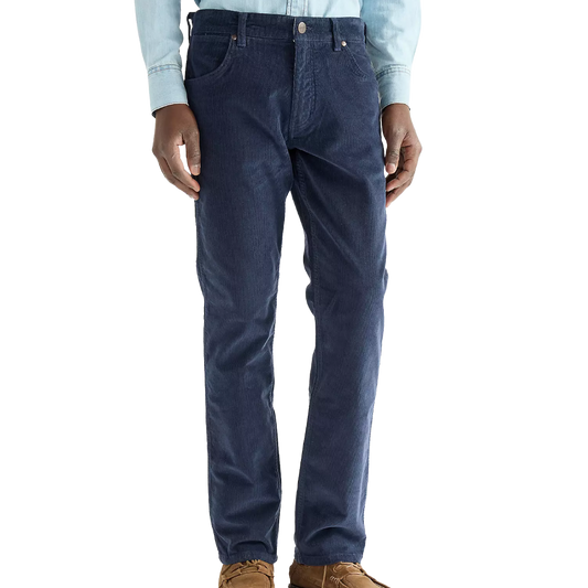 A person wearing dark blue slim-fit jeans, a light blue long-sleeve button-up shirt, and brown shoes, shown from the waist down against a plain white background.