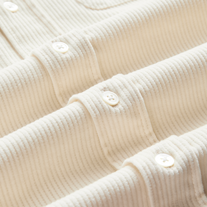 Close-up of a cream-colored ribbed knit top with buttoned collar details and a visible corduroy texture.