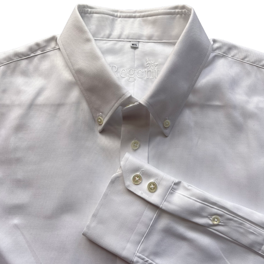 A close-up of a white long-sleeve button-down shirt laid flat, showing the collar, front buttons, and a folded cuff. The inner neck label reads 'Rgnt'.