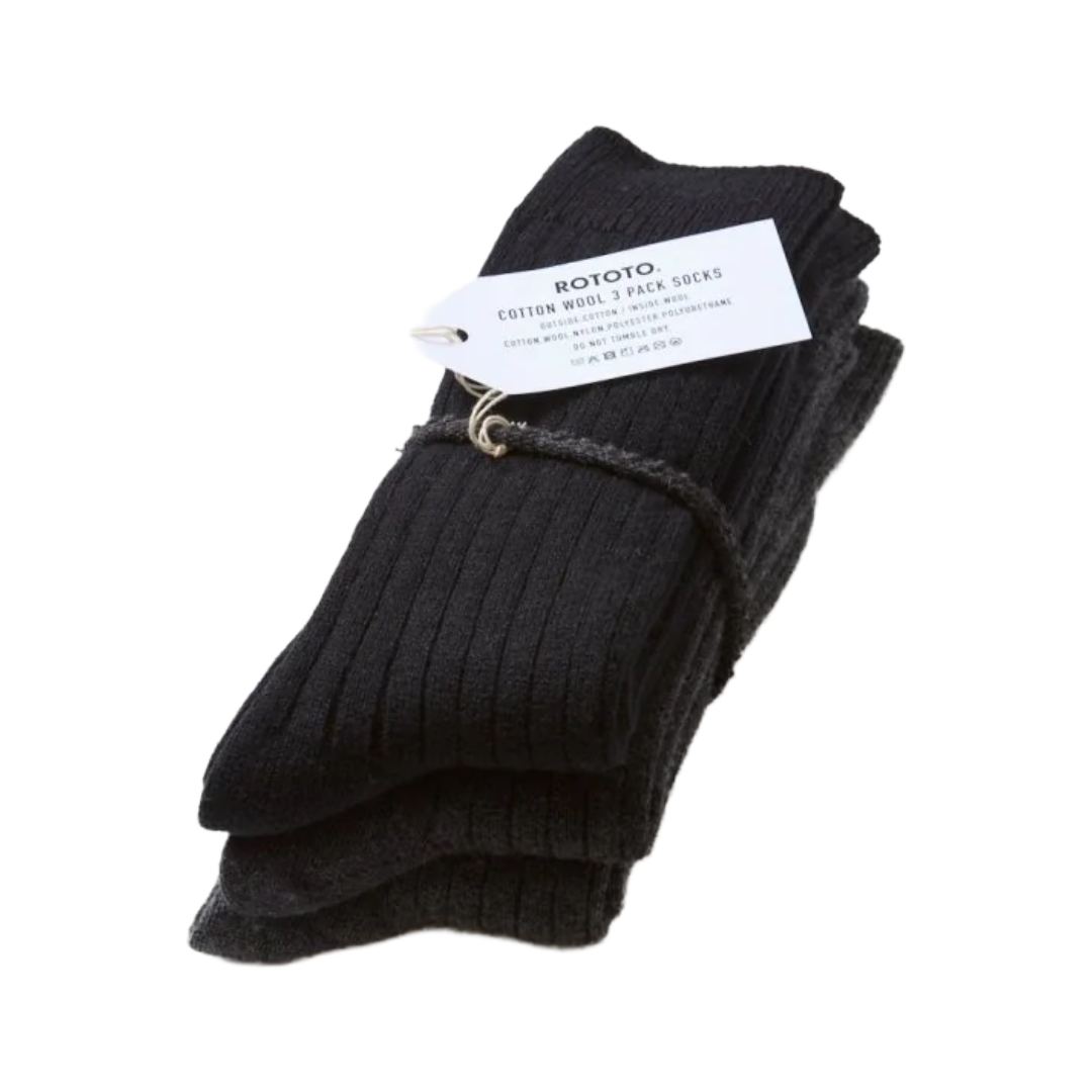 A pair of black ribbed cotton crew socks bundled with a white paper tag and a small metal ring, photographed on a plain white background.