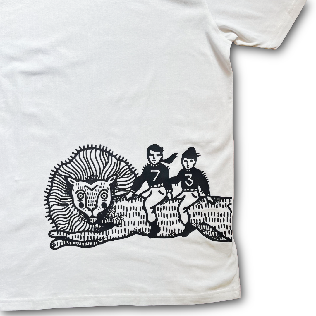 A close-up of a white short-sleeve T-shirt showing a black graphic print of a lion and two children on the front.