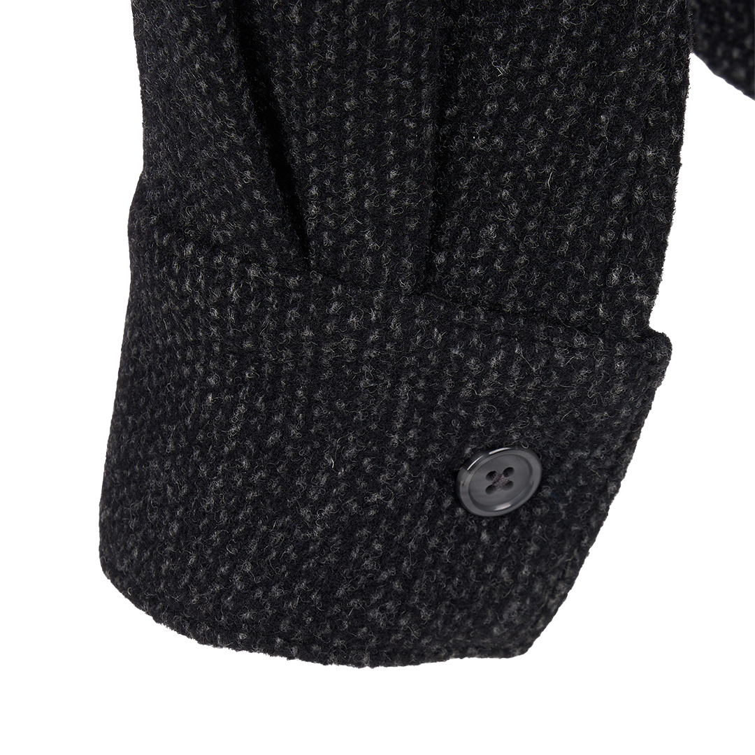 Close-up detail of a dark charcoal tweed jacket sleeve showing a buttoned cuff on a white background.