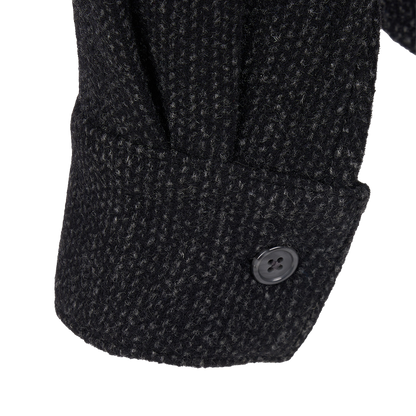 Close-up detail of a dark charcoal tweed jacket sleeve showing a buttoned cuff on a white background.