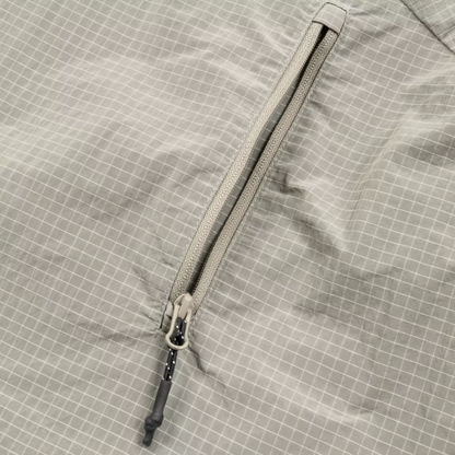 Close-up of a light gray waterproof fabric with a subtle white grid pattern and a matching gray zipper.