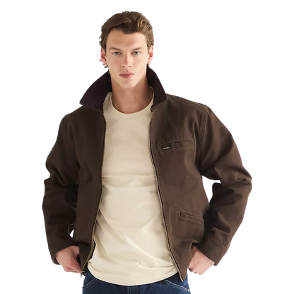 A man wearing a dark brown jacket with a beige crewneck t-shirt and blue jeans, photographed against a solid white background.
