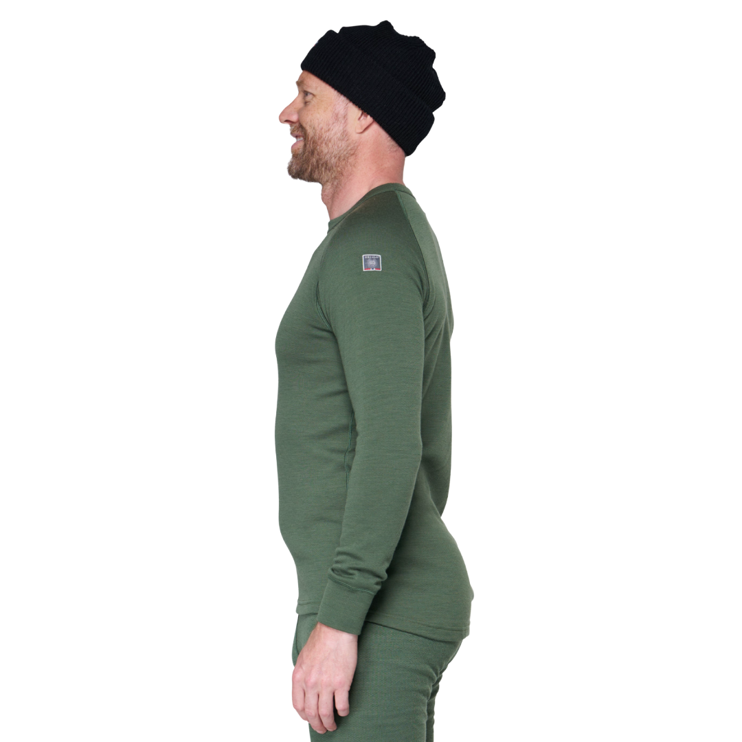 A man in profile wearing a dark green long-sleeve knit top and matching pants, with a black beanie, against a plain white background.