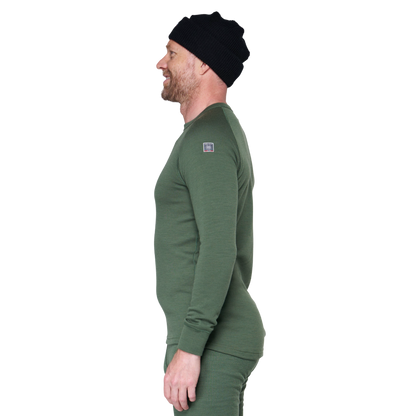 A man in profile wearing a dark green long-sleeve knit top and matching pants, with a black beanie, against a plain white background.