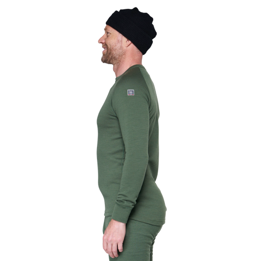 A man in profile wearing a dark green long-sleeve knit top and matching pants, with a black beanie, against a plain white background.