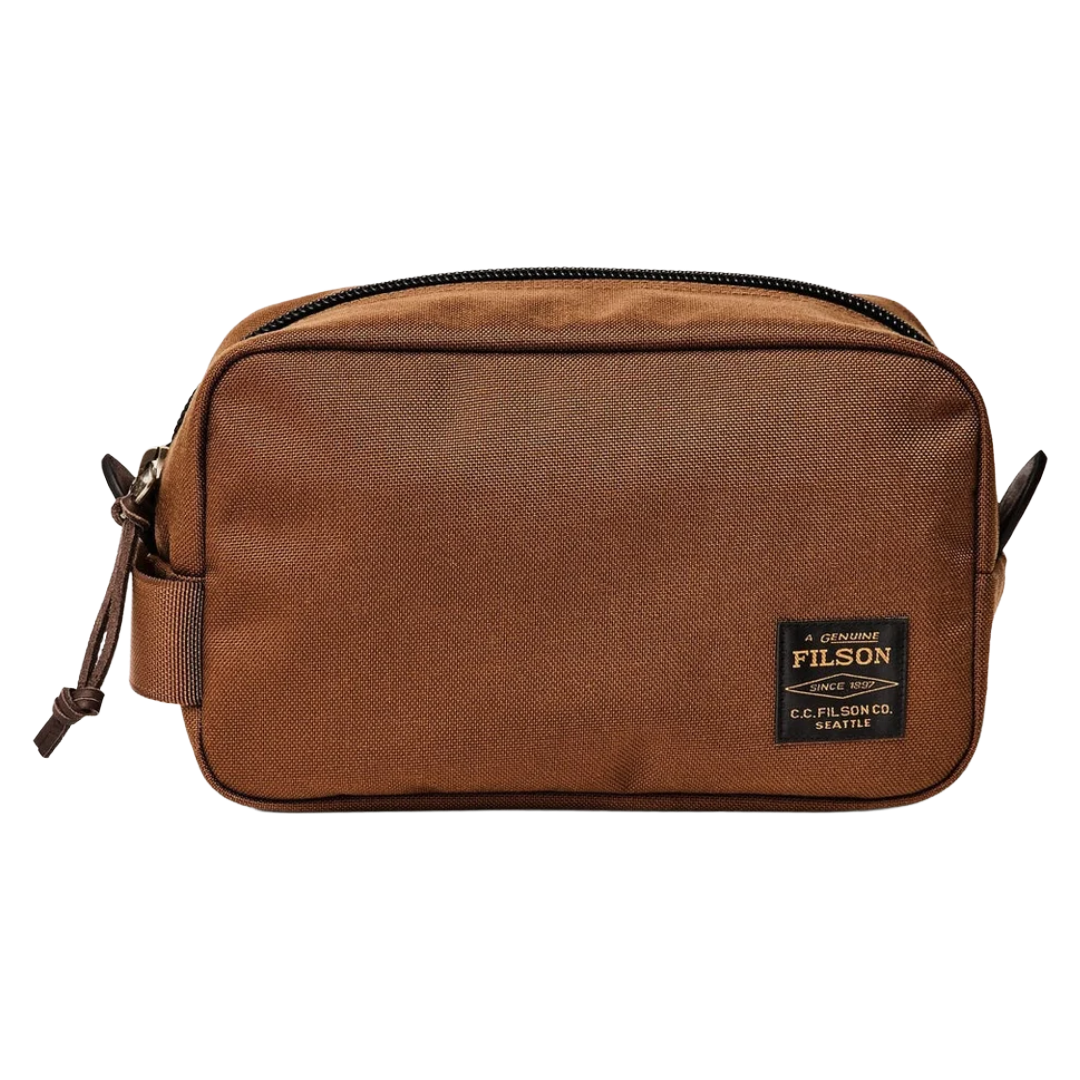 A brown Filson canvas pouch bag with a black zipper and a black brand patch on the front, shown against a plain white background.