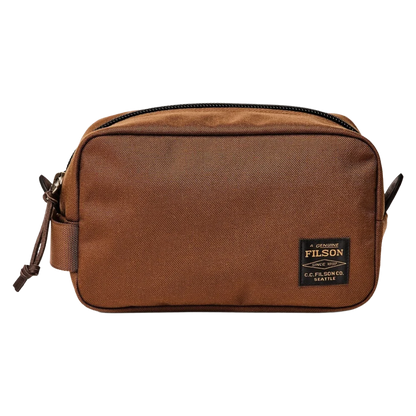 A brown Filson canvas pouch bag with a black zipper and a black brand patch on the front, shown against a plain white background.