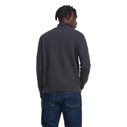 A man viewed from behind wearing a dark charcoal gray knit sweater and blue jeans against a plain white background.