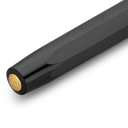 Close-up of a black pen barrel with a gold circular logo accent on the end, photographed on a clean white background.