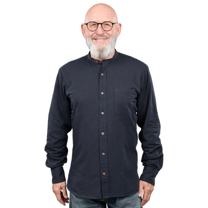A smiling older man with a white beard and glasses wearing a dark navy long-sleeve button-up shirt with a mandarin collar, photographed against a plain white background.