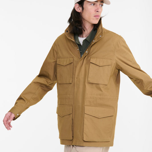 Person wearing a brown jacket and beige cap on a white background