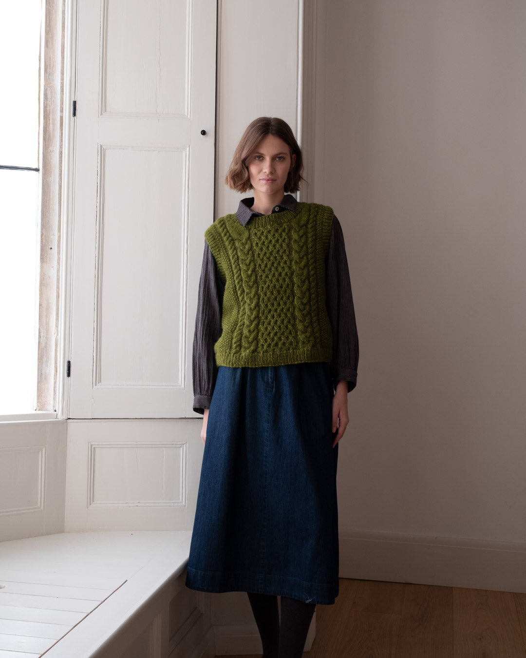Lime green cable knitted vest styled over a dress for layered style