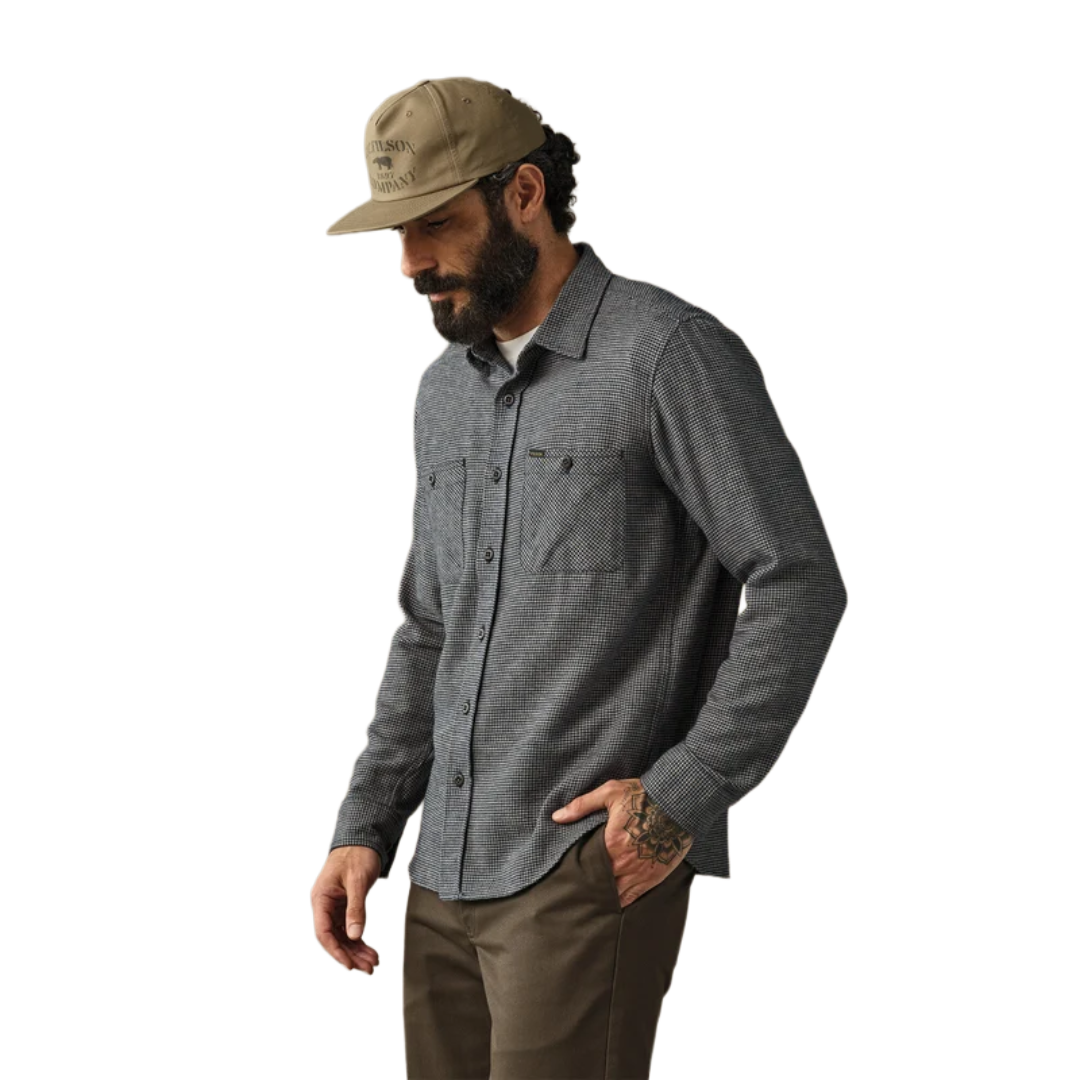 A man wearing a dark gray textured long-sleeve button-up shirt, brown pants, and a tan baseball cap, shown from the waist up against a plain white background.