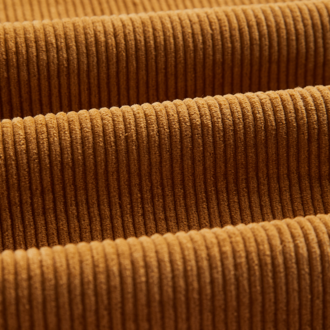 Close-up of a warm brown corduroy fabric with a ribbed texture and soft sheen.